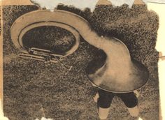 an aerial view of a person standing in the grass with a large metal object on his back
