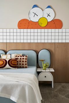 a bed room with a neatly made bed and a cartoon wall hanging above the headboard