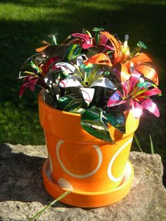 an orange flower pot sitting on top of a rock