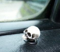 a small white skull sitting on the dashboard of a car in front of a window