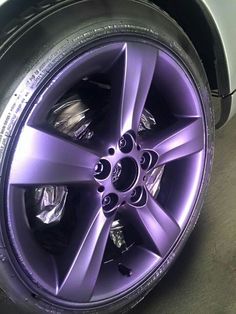 a purple wheel on a white car in a parking lot