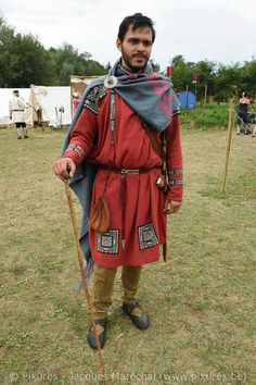 a man dressed in medieval clothing holding a stick