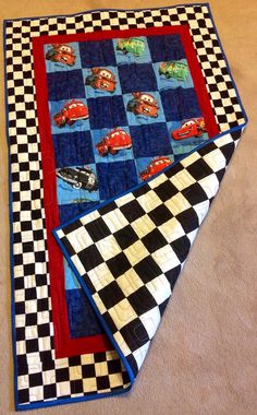 two quilts are laying on the floor next to each other, with cars on them