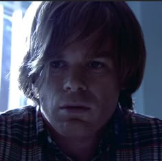 a close up of a person wearing a plaid shirt and looking at something in the distance