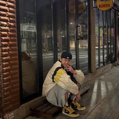 a man sitting on a bench in front of a store with his hand to his mouth