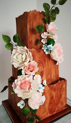 a three tiered wooden cake with flowers on it
