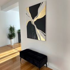 a painting hanging on the wall next to a black bench in front of a potted plant