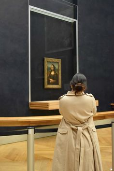 a woman standing in front of a painting looking at it