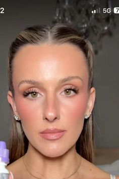 a woman with long hair and makeup looks at the camera while holding an object in her hand