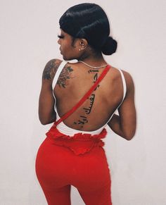 a woman with tattoos on her back is wearing a red skirt
