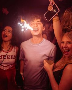 a group of young people holding sparklers in their hands and laughing at the camera