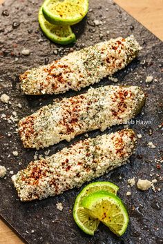 two fish fillets on a cutting board with limes and seasoning next to them