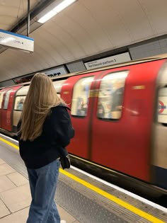 a woman is waiting for the train to arrive at the station as it passes by
