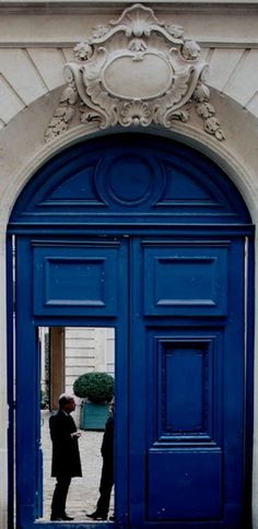 two men standing in front of a blue door