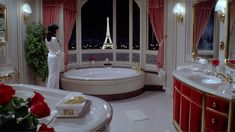 a woman standing in front of a large bathtub next to a window with the eiffel tower in the background