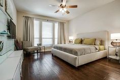 a bedroom with hardwood floors and white walls, along with a large bed in the center