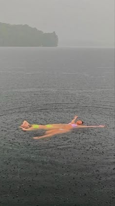 a person floating in the water on top of a body of water with an island in the background