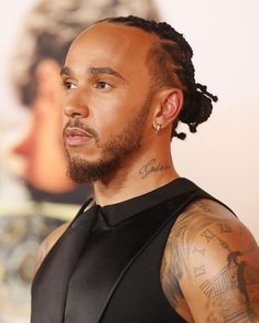 a close up of a person with tattoos on his arm and chest, wearing a black shirt