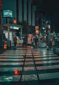 people crossing the street at night with an umbrella