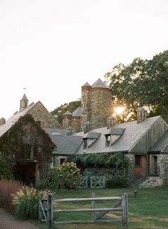an old stone house with a wooden fence in front of it and the sun shining through the windows