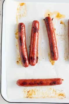 four sausages on a tray with burnt edges