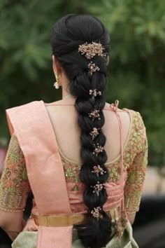 a woman with long black hair wearing a pink sari and braided up into a ponytail