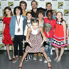 a group of people standing next to each other in front of a wall with comic characters on it