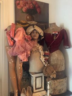 mannequins, hats and dresses are displayed in front of a painting on the wall