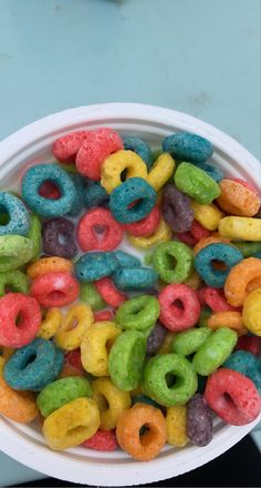a bowl filled with lots of different colored doughnuts on top of a table