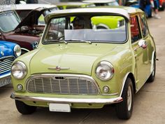 an old green car parked next to other cars