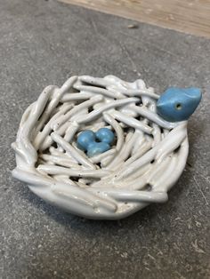 a ceramic bird nest with two blue birds in it