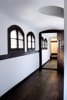 an empty room with wood floors and three arched windows on the wall next to each other