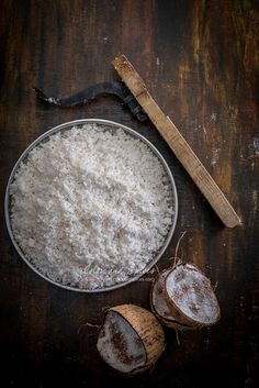 coconuts and flour in a bowl on a wooden table next to a spatula