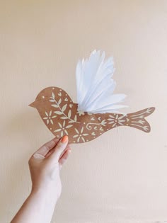 a hand holding a paper bird with white feathers