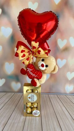 a teddy bear holding a heart shaped balloon on top of a wooden table with hearts in the background