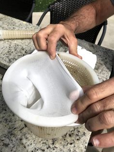 a person is holding a strainer over a table with chairs and tables in the background