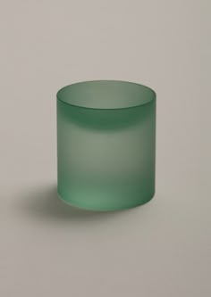 a green glass cup sitting on top of a table