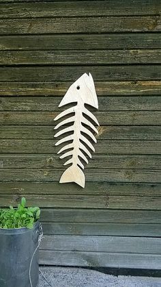 a fish skeleton is mounted to the side of a wooden wall next to a potted plant