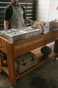 a man standing in front of a table with food on it and the words the tamale company
