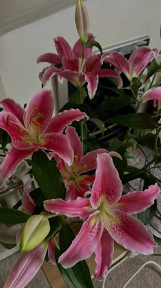 pink lilies are in a vase on the table next to a computer mouse and keyboard