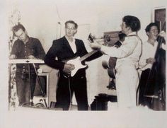 an old black and white photo of two men playing guitars in front of a group of people