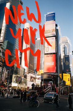 the words new york city written in red on a large city street with tall buildings