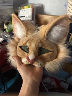 a person holding up a cat mask with long hair on it's head and eyes