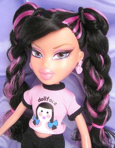 a close up of a doll wearing a pink shirt and black pants with long hair