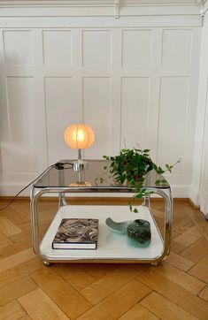 a glass coffee table with a plant on top and a book in front of it