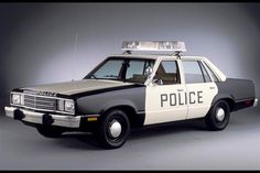 an old police car with its lights on is parked in a studio photo against a gray background