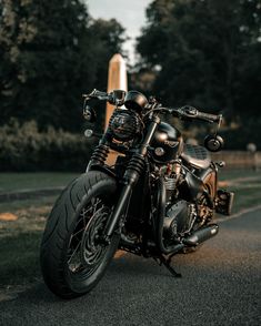 the motorcycle is parked on the side of the road next to some grass and trees