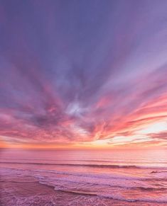 the sun is setting over the ocean with pink and purple clouds in the sky above
