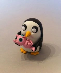 a penguin holding a baby pink object on top of a table