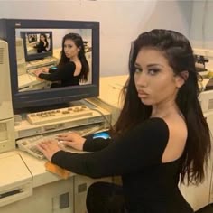 a woman sitting in front of a computer with a keyboard and monitor on her desk
